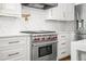 Close-up of kitchen features a Wolf range and marble countertops and backsplash at 315 Mossy Pointe, Duluth, GA 30097