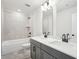 This bright bathroom includes double sinks, a shower-tub and tile flooring at 4785 Marjorie Dr, Cumming, GA 30041