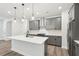 This kitchen features gray cabinets, stainless steel appliances, a tile backsplash, and a quartz countertop island at 4785 Marjorie Dr, Cumming, GA 30041