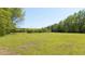 Expansive grassy field with mature trees and a fence line; this property offers space and natural beauty for various activities at 88 Cline Smith Ne Rd, Cartersville, GA 30121
