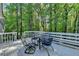 Outdoor back deck featuring outdoor seating, a table, and a railing overlooking a luscious wooded area at 4640 Lambton Cir, Suwanee, GA 30024