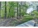View of a spacious backyard with mature trees and landscaping with a stone walkway on the right at 4640 Lambton Cir, Suwanee, GA 30024
