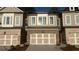 A view of a charming townhome showcasing its brick facade, neutral siding, and attached garages at 102 Birch Tree Way, Cumming, GA 30040