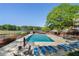 Community pool surrounded by lounge chairs, umbrellas and a lake view, offering a relaxing and scenic recreational area at 105 Woodmeade Nw Way, Marietta, GA 30064