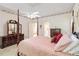 Bright main bedroom featuring tray ceiling, four-poster bed, and hardwood furniture at 219 Garden W Walk, Hampton, GA 30228