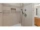Close up of the elegant shower showcasing neutral tile, shelving, and chrome fixtures at 809 Kirby Dr, Woodstock, GA 30188