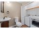 Bathroom with a toilet, sink, washer, and dryer, complemented by wood-look flooring at 223 Chads Ford Way, Roswell, GA 30076