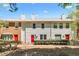 Charming townhome featuring a brick and vinyl exterior, manicured landscaping, and inviting red front doors at 223 Chads Ford Way, Roswell, GA 30076