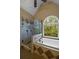 Bright bathroom featuring a glass-enclosed shower and a luxurious soaking tub next to a large arched window overlooking greenery at 2340 Bexford Vw, Cumming, GA 30041