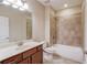Bathroom with tiled shower over tub, cherry vanity, and a neutral color palette at 4321 Lanier Ridge Walk # 1704, Cumming, GA 30041