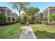 View of condo complex with screened porches, manicured lawns, and walkways lined with decorative shrubs and mature trees at 55 Delmont Ne Dr # D1, Atlanta, GA 30305