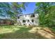 View of the backyard of a two-story home surrounded by mature trees and a well-maintained lawn at 1027 Mount Airy Sw Dr, Atlanta, GA 30311