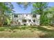View of the backyard of a two-story home with a small porch surrounded by mature trees and a well-maintained lawn at 1027 Mount Airy Sw Dr, Atlanta, GA 30311