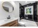 Modern bathroom featuring black tiled accent wall, separate tub, modern vanity, and a round mirror at 1027 Mount Airy Sw Dr, Atlanta, GA 30311