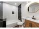 Modern bathroom featuring a white vanity, a black-and-white tiled shower, and a round mirror at 1027 Mount Airy Sw Dr, Atlanta, GA 30311