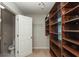 Walk-in closet shows wooden shelves and hanging space next to an open bathroom doorway at 5260 Sherwood Way, Cumming, GA 30040