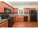 Cozy kitchen features wood cabinets, granite countertops, black appliances, and mosaic tile backsplash at 5260 Sherwood Way, Cumming, GA 30040