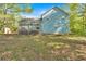 Spacious backyard view of the house with a wooden deck, mature trees, and some brush at 111 Amberwood Ln, Euharlee, GA 30145