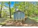 Blue storage shed with white trim sitting in a backyard with mature trees at 111 Amberwood Ln, Euharlee, GA 30145