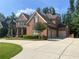 Two-story brick home with manicured lawn, and a three car garage at 2331 Kinsale Nw Pt, Kennesaw, GA 30152