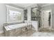 A luxurious bath area with a soaking tub, tiled surround, shower, and decorative window accents at 5422 Heyward Square Pl, Marietta, GA 30068