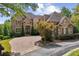 Beautiful brick and stone two-story home with a well-manicured lawn and circular brick driveway at 5422 Heyward Square Pl, Marietta, GA 30068