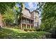 Back exterior featuring brick facade, multiple decks, and expansive lawn with mature trees at 5422 Heyward Square Pl, Marietta, GA 30068