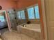 Bathroom featuring a soaking tub with tiled surround and glass enclosed shower with shuttered window at 187 Slate Dr, Buford, GA 30518