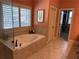Bright bathroom featuring a soaking tub with tiled surround and shuttered window at 187 Slate Dr, Buford, GA 30518