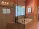 Elegant bathroom featuring a soaking tub, tiled shower, and natural light from shuttered window at 187 Slate Dr, Buford, GA 30518