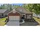 Aerial view of charming brick home with manicured lawn, two-car garage, and mature trees at 4930 Kings Common Way, Cumming, GA 30040