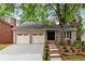 Attractive brick home with a two-car garage, front yard landscaping, and a paved driveway at 1205 Club Walk Ne Dr, Brookhaven, GA 30319