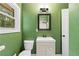 Bathroom featuring white toilet and single sink vanity with modern mirror and green walls at 1217 Topaz Ln, Villa Rica, GA 30180