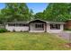 Charming single-story home with a well-manicured lawn, fresh white paint, and a welcoming pink front door at 1217 Topaz Ln, Villa Rica, GA 30180