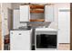 This laundry room includes a washer, dryer, wooden decorative shelves, and white cabinets at 1217 Topaz Ln, Villa Rica, GA 30180