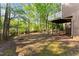 Large backyard features a covered deck and a mix of grass and leaves with trees surrounding the fenced in perimeter at 440 Hunt River Way, Suwanee, GA 30024