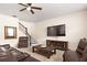 Cozy living room with a fireplace, ceiling fan, staircase, and comfortable leather seating at 1318 Crestwind Nw Rd, Kennesaw, GA 30152