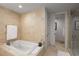 Luxurious bathroom features a soaking tub, travertine walls, and a glass shower door at 3630 Peachtree Ne Rd # 3207, Atlanta, GA 30326