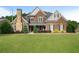 Inviting two-story brick home featuring lush lawn, manicured shrubs, and a striking stone chimney at 416 Battlefield Creek Dr, Marietta, GA 30064