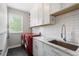 Neat laundry room area with white cabinets, tile backsplash, stainless steel sink, and modern appliances at 416 Battlefield Creek Dr, Marietta, GA 30064