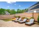 Backyard stone patio features lounge chairs and a retaining wall with manicured shrubs and a wooden privacy fence at 903 Shaftoe Nw St, Kennesaw, GA 30152