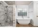 Modern bathroom features a glass shower, a freestanding tub, and a decorative window at 903 Shaftoe Nw St, Kennesaw, GA 30152