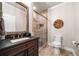 Elegant bathroom featuring stone tile, a wooden-framed mirror, and a glass-enclosed shower with rustic charm at 903 Shaftoe Nw St, Kennesaw, GA 30152