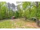 Lush backyard featuring mature trees, a small shed with a porch, and a fire pit area for outdoor enjoyment at 2619 Kellogg Creek Rd, Acworth, GA 30102