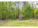 Backyard view with a shed, fire pit, and chain link fence bordering the wooded area at 2619 Kellogg Creek Rd, Acworth, GA 30102