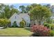 Elegant two-story home featuring a manicured lawn, mature trees, and vibrant red flowers in the front yard at 2990 Byrons Green Ct, Marietta, GA 30062