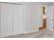 A carpeted bedroom with light-colored walls, a view of the kitchen, and a set of folding closet doors at 2009 Shipwreck Ct, Buford, GA 30518