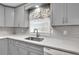 This kitchen is equipped with gray cabinets, a stainless steel sink, white countertops and patterned backsplash at 2009 Shipwreck Ct, Buford, GA 30518