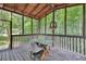Screened porch with wood beam ceiling, seating, and wooded view at 2009 Shipwreck Ct, Buford, GA 30518