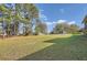 Spacious backyard with a large grassy area, mature trees, and a shed in the distance at 2376 Falls River Dr, Lithia Springs, GA 30122